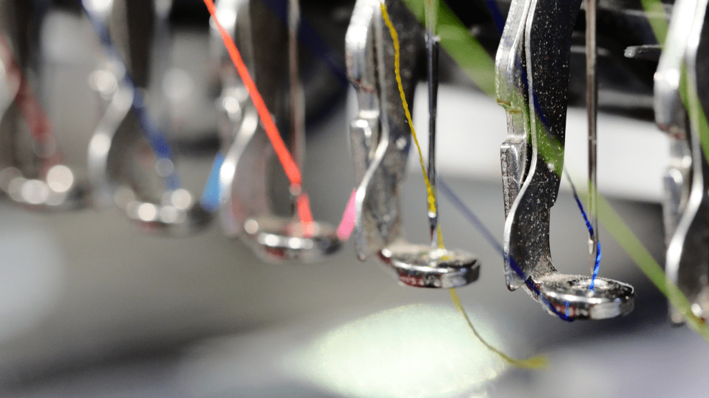 ภาพระยะใกล้ของหัว จักรปักคอมพิวเตอร์หลายเข็ม แสดงให้เห็น ถึงเทคโนโลยีการผลิตที่ทันสมัยและความแม่นยำในการปัก