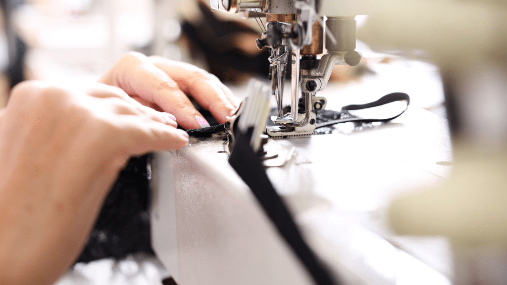 ช่างฝีมือกำลังเย็บผ้าสี ดำด้วยจักรเย็บผ้า อุตสาหกรรมอย่าง ประณีต